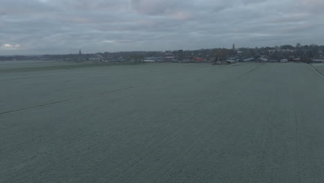 Luftaufnahme-Von-Gefrorenen-Wiesen-Mit-Der-Skyline-Einer-Stadt-Im-Hintergrund