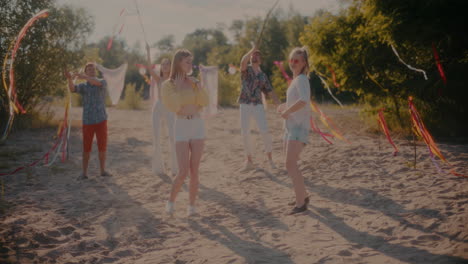 young women dancing against friends grooving with ribbons