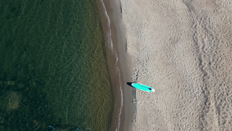 Wellen-Treffen-Langsam-Auf-Einen-Wunderschönen,-Einsamen-Strand,-Sup-Board-Auf-Sand