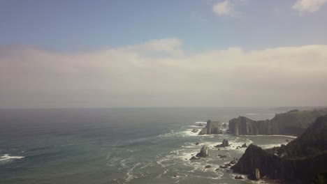 Coastal-ocean-with-rocky-cliffs-and-surging-waves-on-a-sunny-day