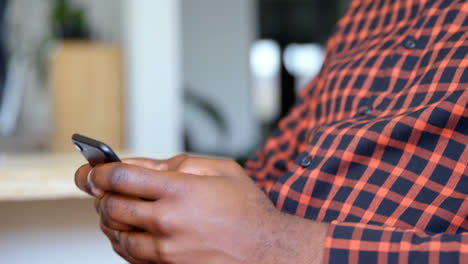 Side-view-of-young-black-businessman-working-on-smartphone-in-a-modern-office-4k