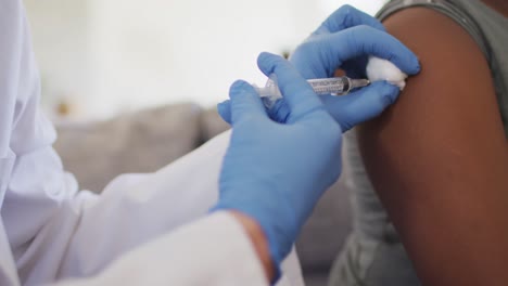 close up of african american girl and caucasian female doctor vaccinating