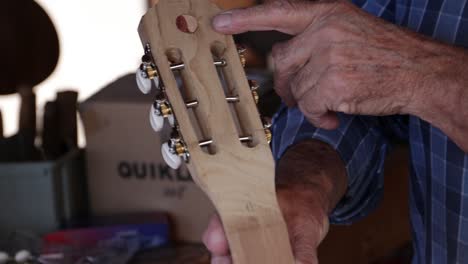luthier's hand indicate tao symbol engraved on headstock peghead of classical guitar