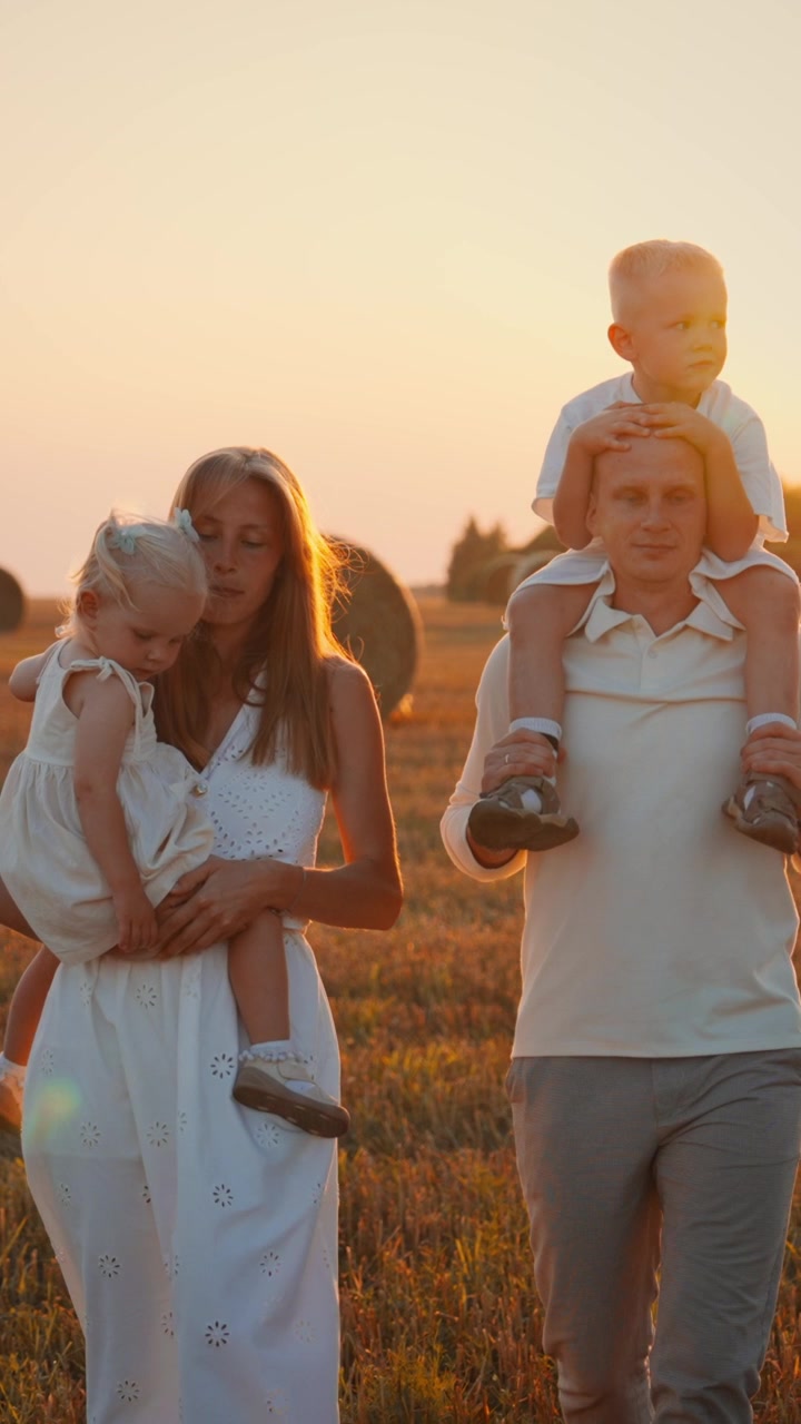 Giovane famiglia che passeggia in un campo al tramonto
