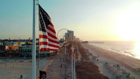 Aerial-Rise-up-Shot-of-Myrtle-Beach-Coastline-with-American-Flag-in-the-Foreground
