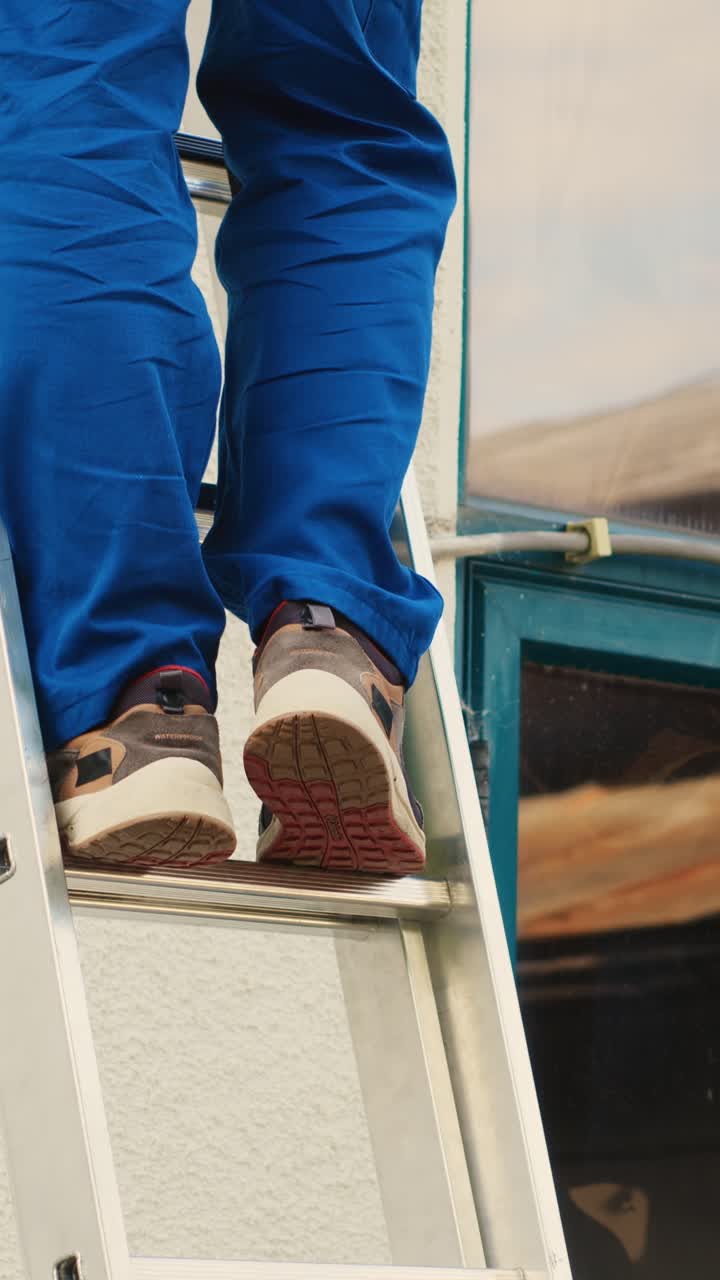 Vertical video Technician holds drill climbing ladder