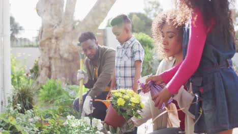 padres afrodescendientes felices con hijos haciendo jardinería juntos