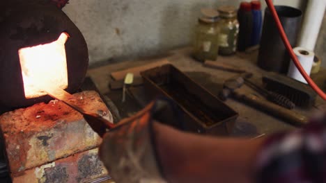 manos cercanas de un hombre caucásico fabricante de cuchillos en un taller usando horno y haciendo cuchillos