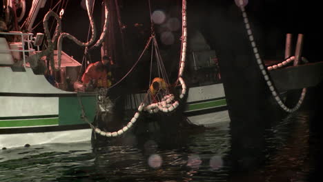 a crew member reaches into a fishing vessels net