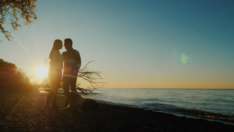 couple with dog by lake at sunset
