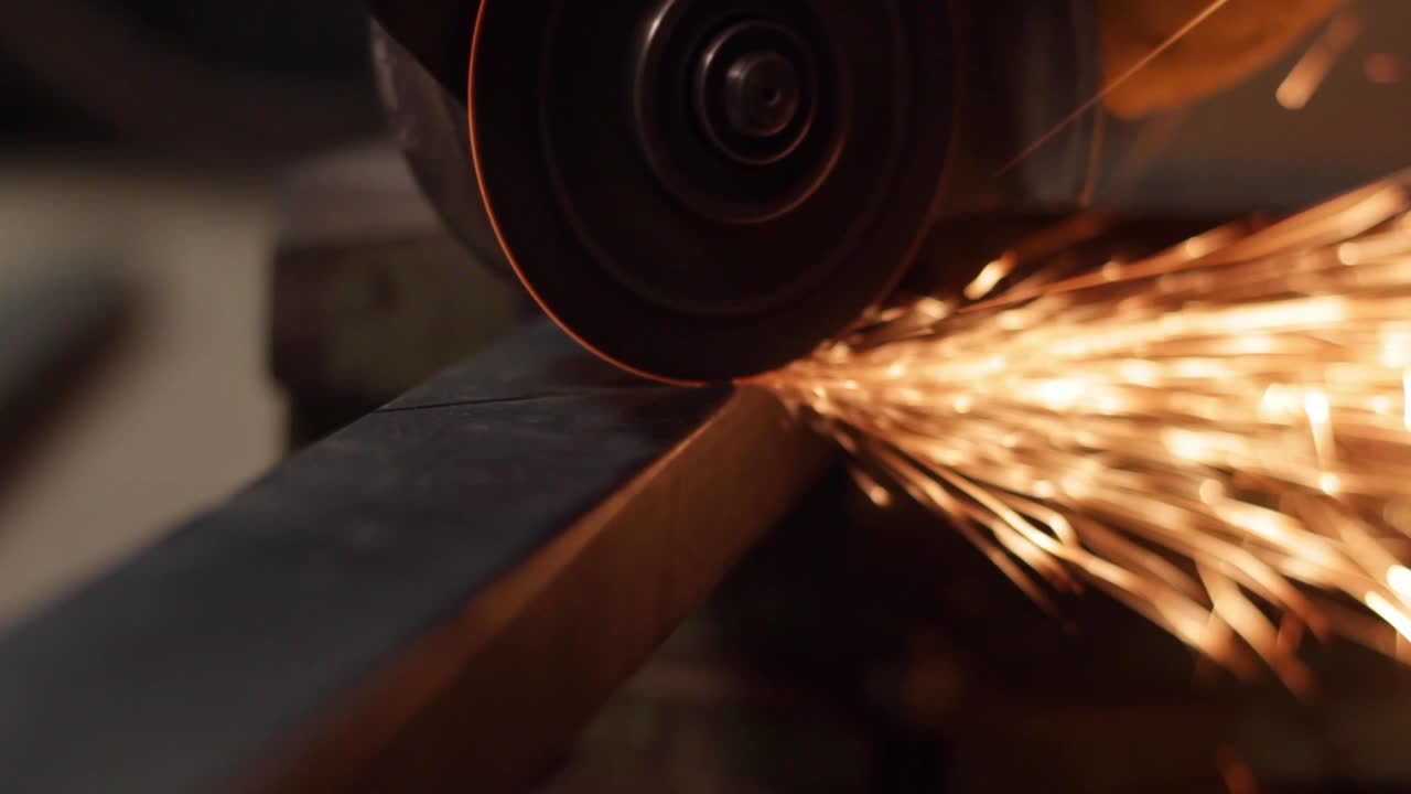 Saw blade grinder with sparks slicing a iron rod, closeup