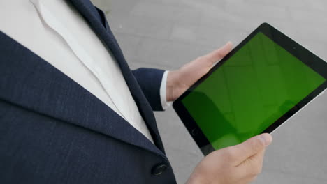 businessman working on digital tablet at street. employee holding pad outside