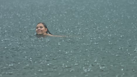 a young woman expressing freedom swimming outside in open water in the rain climate