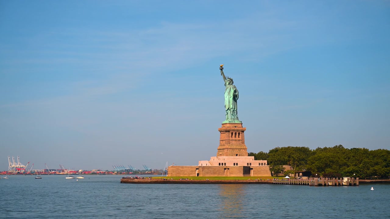 Patung Liberty di atas alas batunya. Monumen tembaga hijau itu berdiri tegak di Pulau Liberty dengan latar langit biru cerah selama musim panas