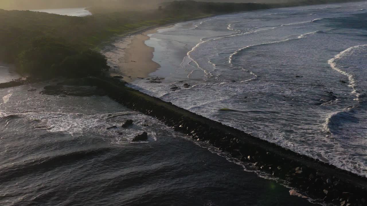 Aerial footage captures waves crashing along Brunswick Heads' coastline, showcasing dynamic ocean movement and serene beach scenery