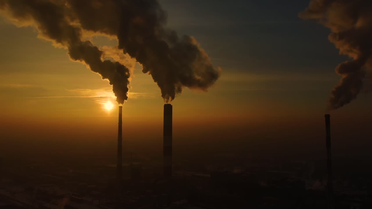Power Plant emissions seen above the city during sunrise. Environmental pollution. Factory pipe polluting air.Panorama sunset. Smoking pipes Aerial view,