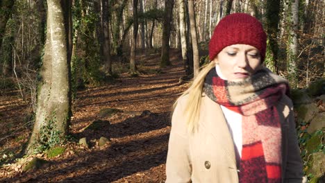 woman in fall clothing with wistful look walks past camera in autum forest