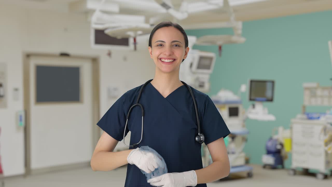 Doctora india feliz quitándose los guantes y el gorro después de una operación exitosa