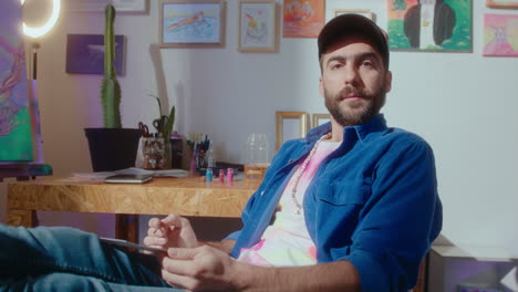 portrait of young artist sitting in creative studio with legs on table