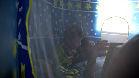 Mexican-latin-brunette-mother-reading-a-book-to-her-son-laying-inside-his-castle-tent-having-a-moment-together