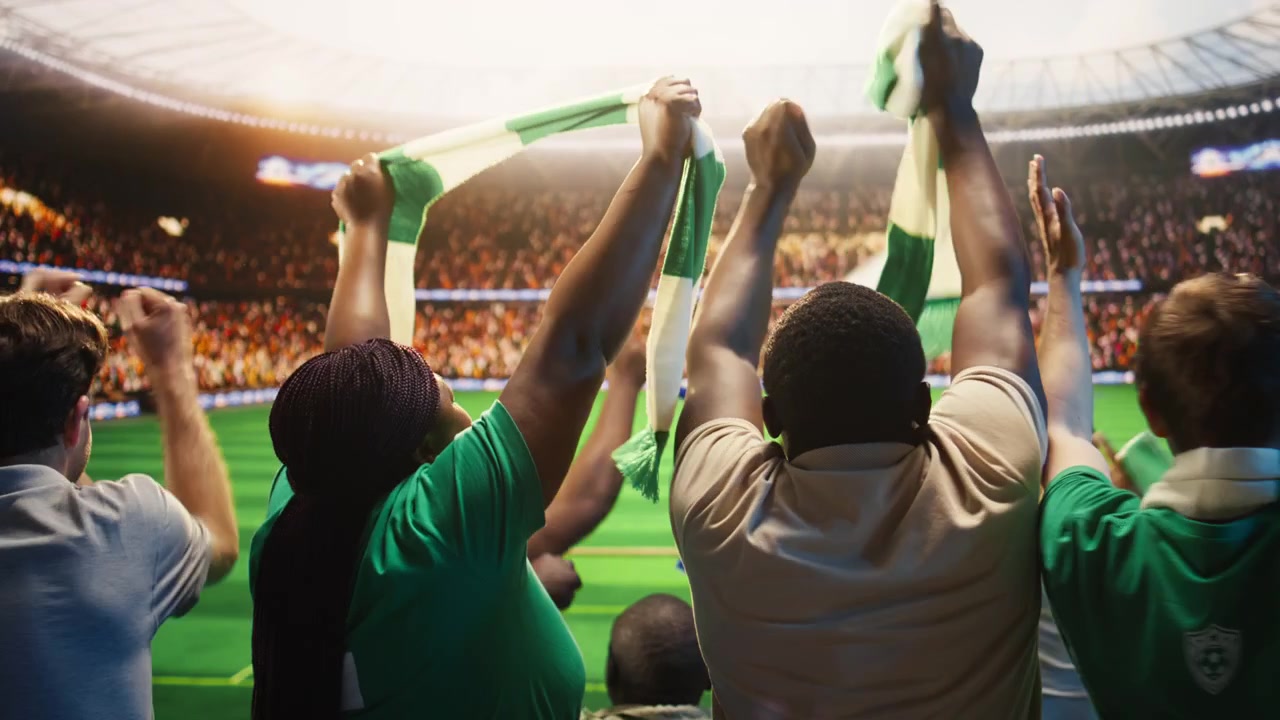 Vista trasera de aficionados felices celebrando un gol desde el estadio durante un partido de fútbol