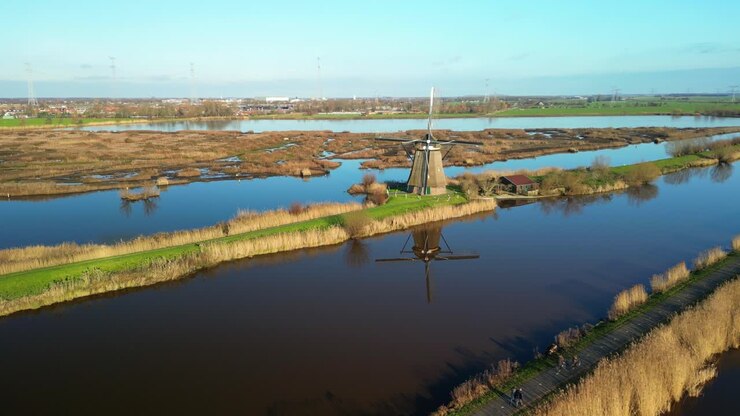 Riflesso di un mulino a vento tradizionale in un canale calmo a Kinderdijk in una giornata di sole.
