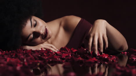 portrait beautiful african american woman playing with rose petals falling sensual female dreaming of intimate fantasy romance in red background valentines day concept