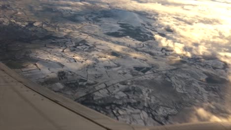 bancos de jet a la izquierda después del despegue y mirando por la ventana del avión mientras se nivela mirando el suelo recién cubierto de nieve en el norte