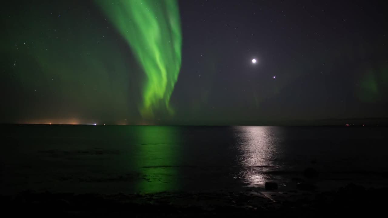 Time-lapse of northern lights shimmering over a calm lake at night