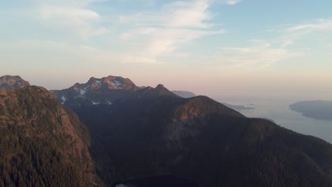 Sunset-Aerial-Drone-Panning-Shot-Over-Snow-Capped-Mountain-Rocky-Landscape-with-Blue-and-Orange-Sky-in-Pacific-Ranges-Canada-BC-4K