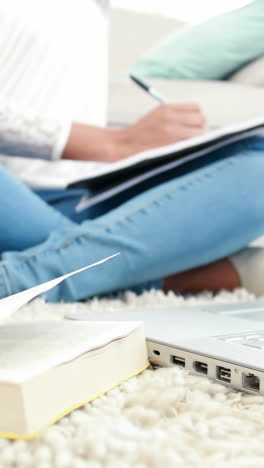 mujer sentada en el suelo escribiendo en el bloc de notas