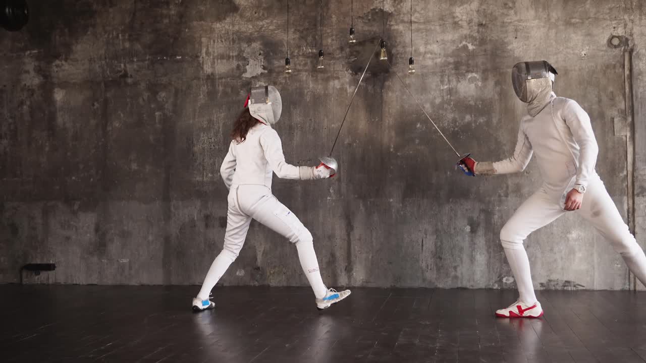 두 명의 펜싱 선수가 행동하고 있습니다.