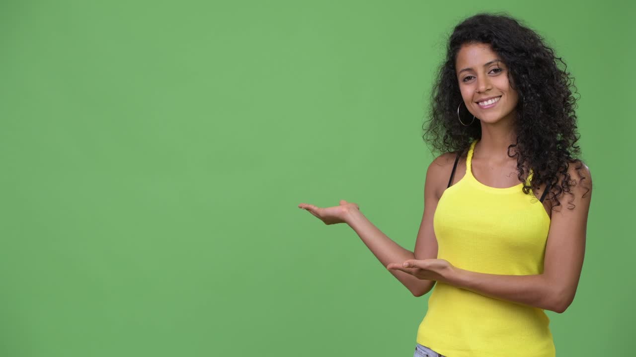 Young beautiful Hispanic woman showing something