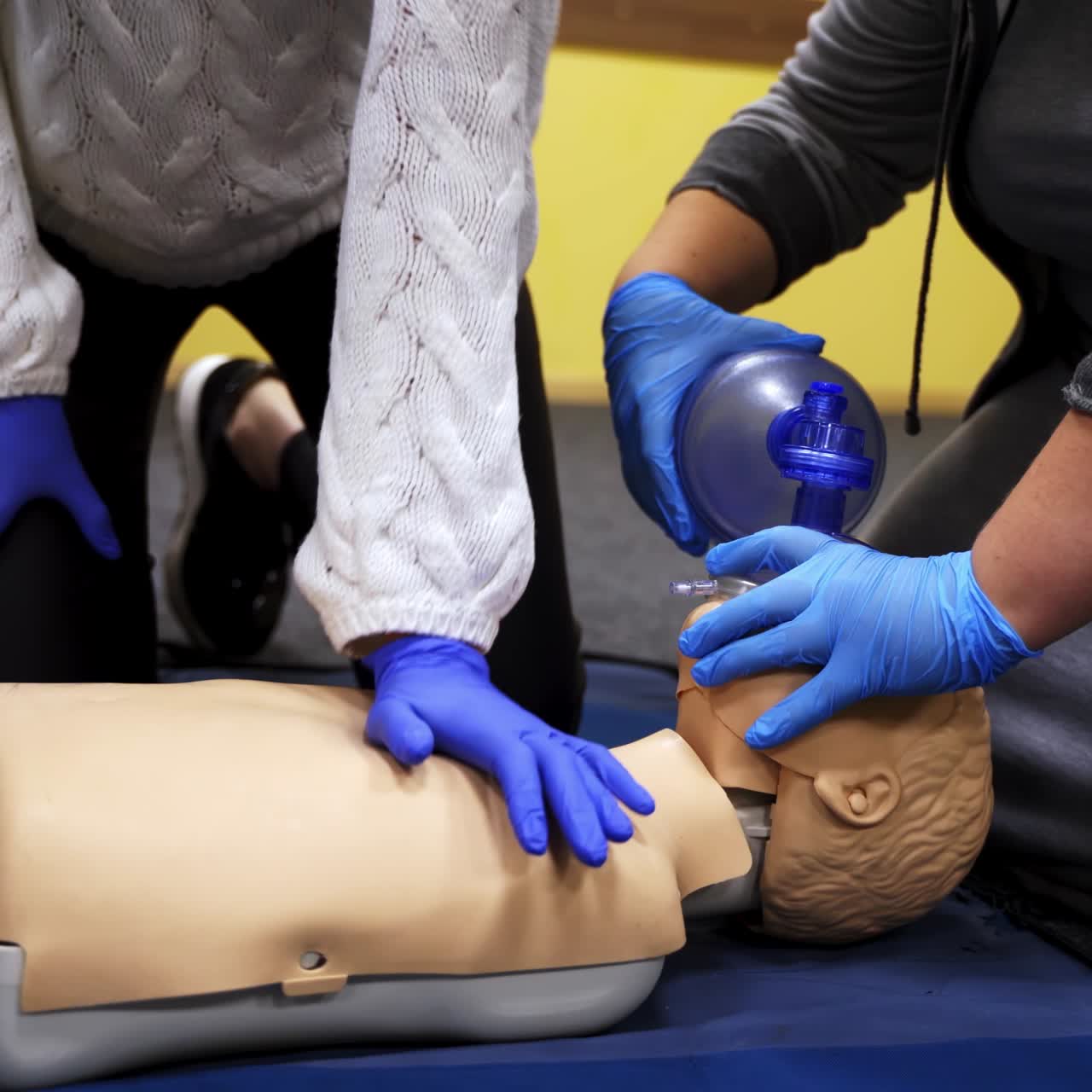 First aid reanimation. Women in safety gloves trying resuscitation technique on dummy. Cardiopulmonary training on a mannequin. Healthcare and medical concept