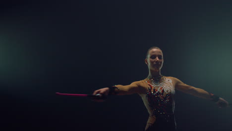 una mujer bonita dando vueltas con un mazo, una gimnasta rítmica ensayando en el interior.