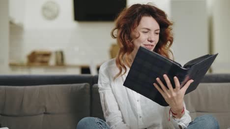 mujer emocionada viendo un libro de fotos en la cocina abierta. mujer alegre sosteniendo un libro de fotos