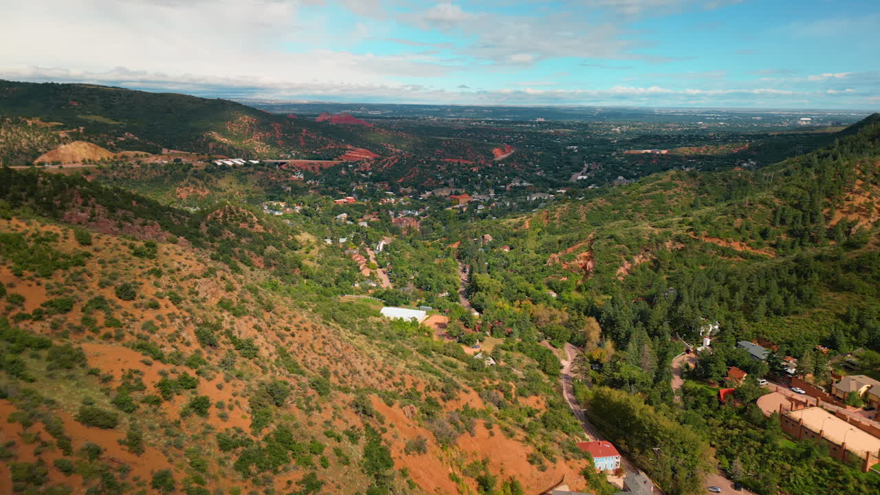 Scarce greenery covering the rocky landscape. Houses located in the valley at the mountain foot. Utah, USA