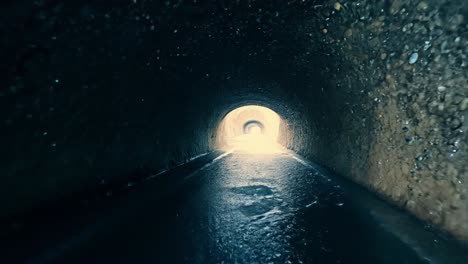 light slowly fills a dark tunnel as water flows, creating a sense of hope and mystery within the underground passage