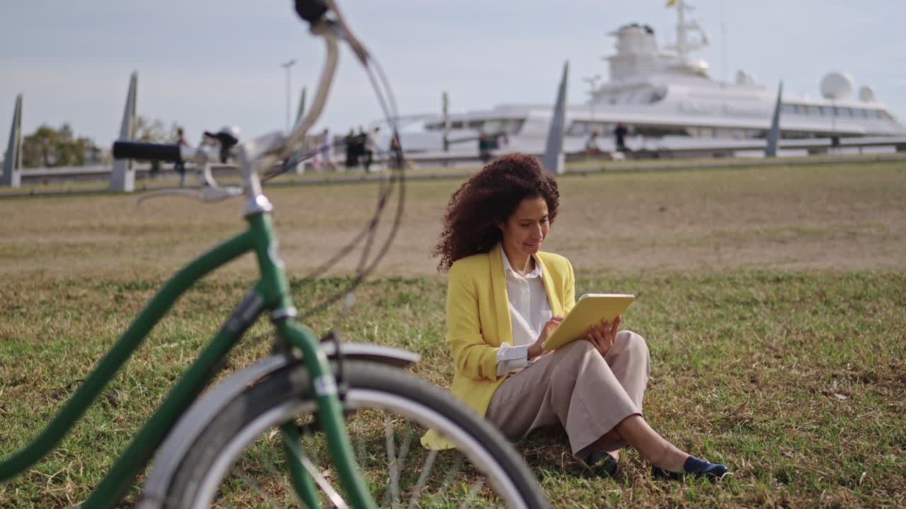 Woman using tablet in park with bicycle