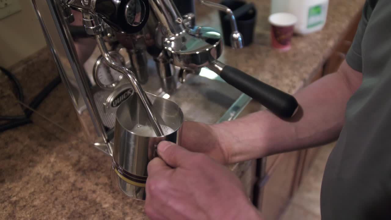 Barista steaming milk in machine to make coffee, latte, cappuccino, close up