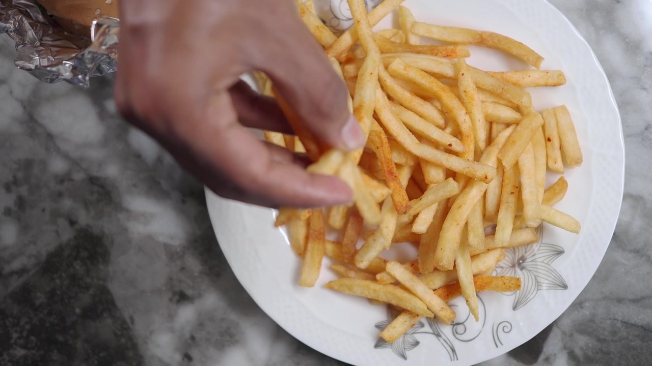 Hand Picking French Fries from a Plate