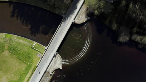 static aerial shot of cyclist crossing dam in yorkshire, england