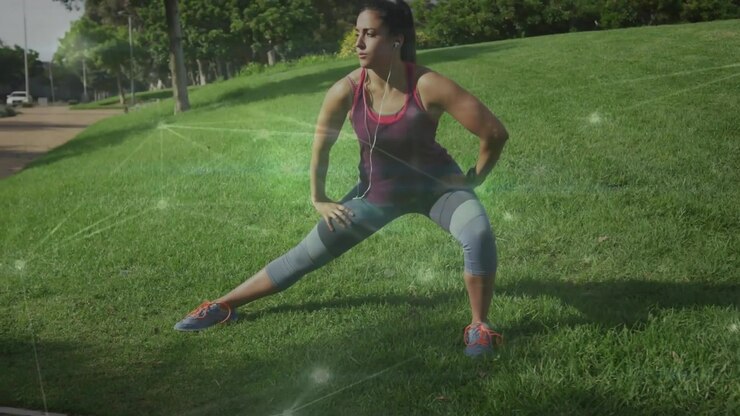 Donna che inizia il riscaldamento fitness al parco, passando a un affondo laterale destro con una sovrapposizione verde che mostra il movimento.