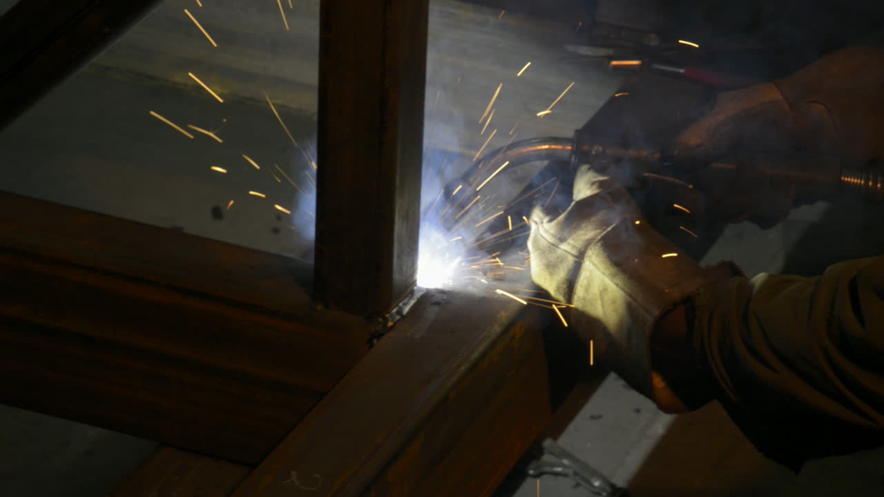 Sparks fly as a factory worker welds steel beams