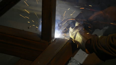 sparks fly as a factory worker welds steel beams