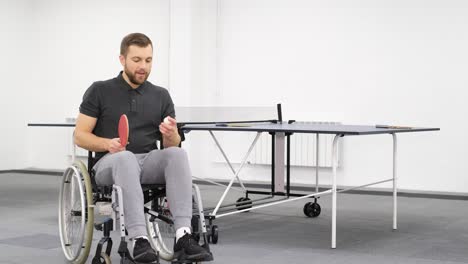 Attractive Young Disabled Man Playing with a Ping Pong Racket Attractive Young Disabled Man Playing with a Ping Pong Racket a Disabled Man in a Wheelchair Plays Table Tennis Hits the Ball with a Racket
