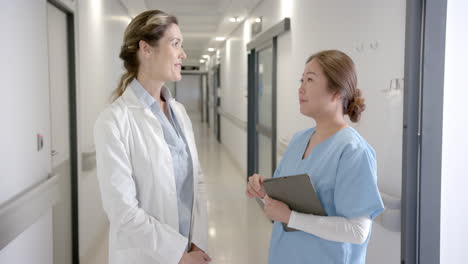 Portrait-of-happy-diverse-female-doctors-with-tablet-in-hospital-corridor,-slow-motion