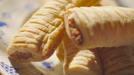 bright natural sunlight of sausage rolls on plate after baking. delicious traditional english fresh bakery product. british snack cuisine. pork meat wrapped in puff pastry.