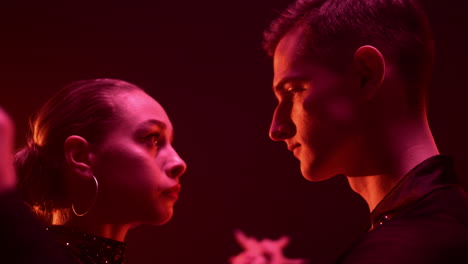 ballroom dancers looking each other indoors. dance couple holding hands inside.