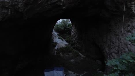 aerial drone shot entering a dark and mysterious cave surrounded by vegetation